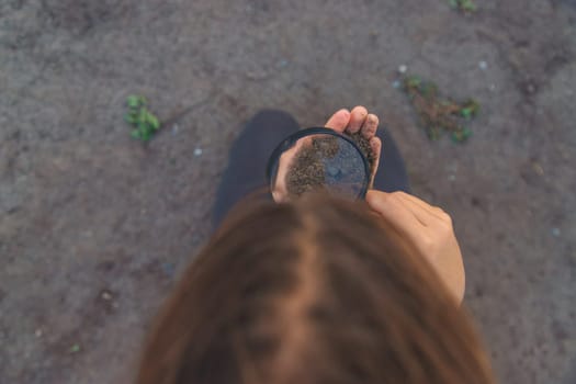 A child looks at the soil through a magnifying glass. Selective focus. Kid.