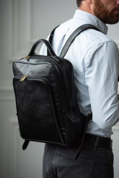 A fashionable man stands with a bag in a contemporary room, embodying urban style and professionalism.