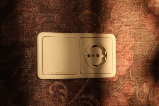 A modern electrical outlet on a floralpatterned wall, blending functionality with decor aesthetics