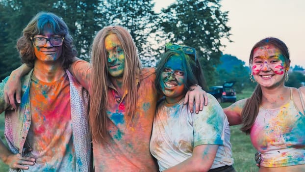 Friends covered with colorful powder paint are hugging and celebrating holi festival