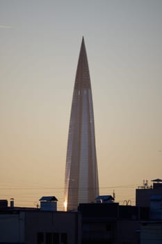 A sleek and modern skyscraper rises majestically against the vibrant sunset backdrop in a dynamic urban landscape