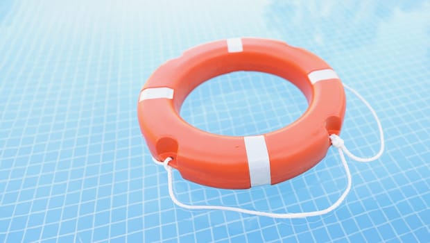 Red lifebuoy in the pool, blue water, close-up. Drowning assistance, safety when learning to swim, protection