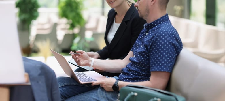 A man with a laptop and a woman with a tablet are talking, close-up, blurry. Negotiating on the street, discussing strategy