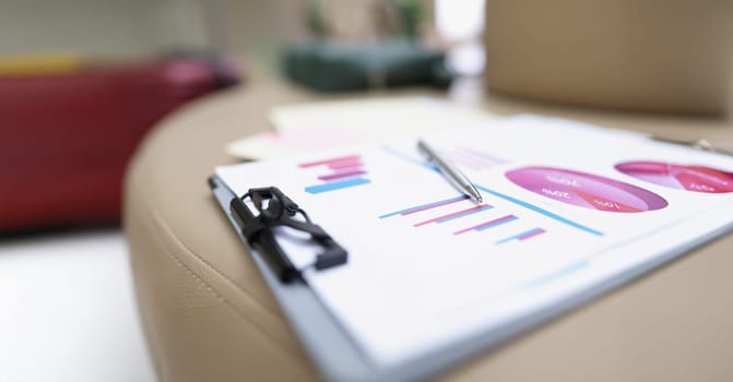 A folder with documents lies on a leather surface, close-up, blurry. Audit preparation, color chart and graph on paper