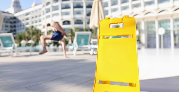 Yellow plastic wet floor warning signs on the background of a falling man, close-up, blurry. Traumatic slippery