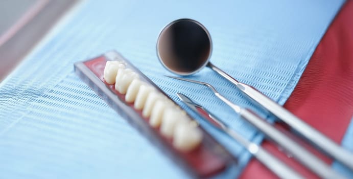 Orthodontist tools and dental bridge, close-up, blurry. Dental prosthetics, implantation in the mouth, veneers