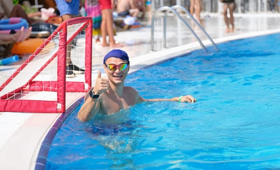 Sports man in the pool smiling and showing thumbs up, close-up. Polo player, goalkeeper. Team play, swimming