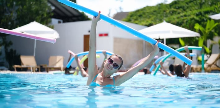 Sportive woman doing exercises in the pool, water aerobics, close-up. Aquafitness for weight loss. Relaxation on the water