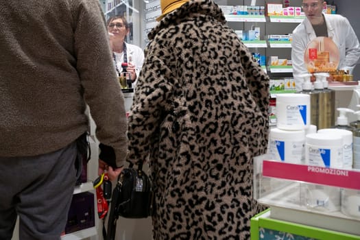 Cremona, Italy - November 20th 2024 Italian customers buying medicine and cosmetics, having a conversation with pharmacist and chemist in a pharmacy in cremona, italy