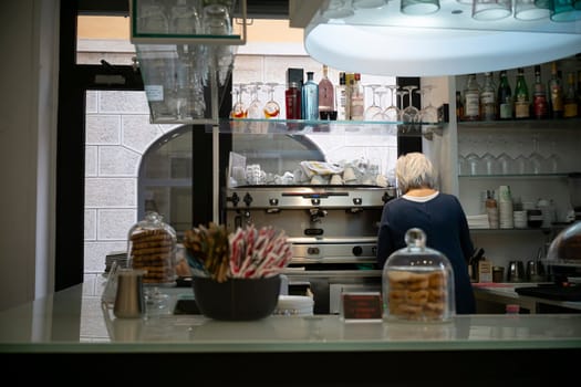 Cremona, Italy - November 20th 2024 Barista working behind the counter in a typical cafe in cremona, italy, getting ready to serve customers