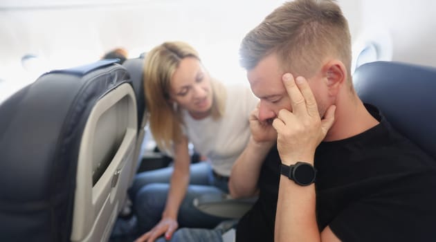 A man calms himself down in the aircraft cabin, aerophobia, close-up. The family travels, flight. Anxiety, turbulence