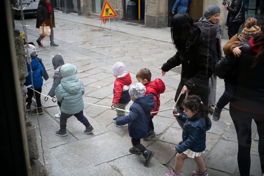 Cremona, Italy - November 20th 2024 Group of kindergarten children walking in line holding a rope with their teachers in cremona, italy
