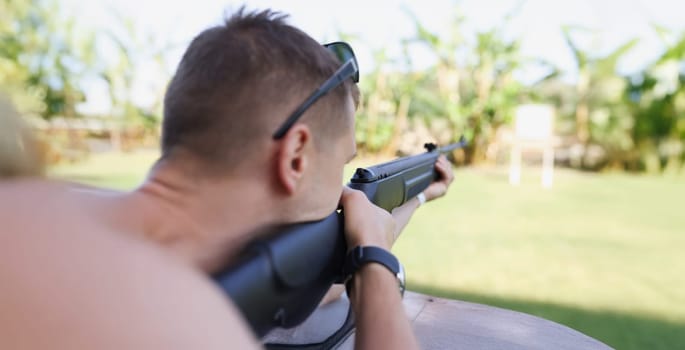 A man is aiming at a target with a gun, close-up, blurry. Weapon shooting training, preparation for biathlon competition