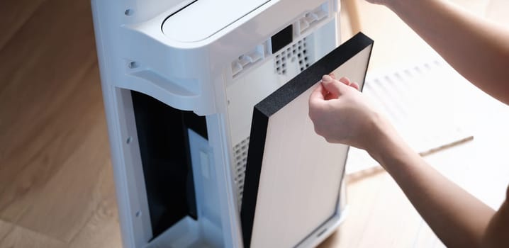 A woman removes the filter from the air ionizer, close-up. Household appliances, air purification, air conditioning, equipment