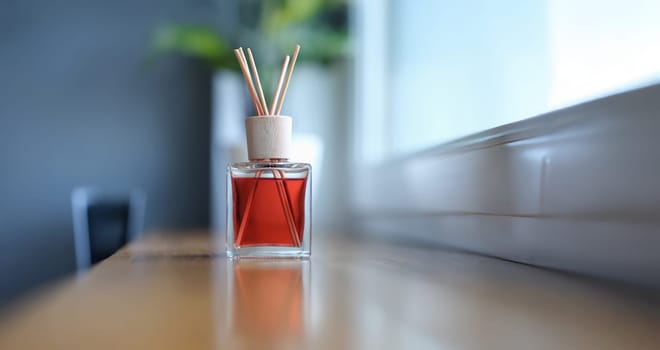 Bamboo sticks fragrance for the room stands near the window, close-up, blurry. Spread the scent. Aromatherapy