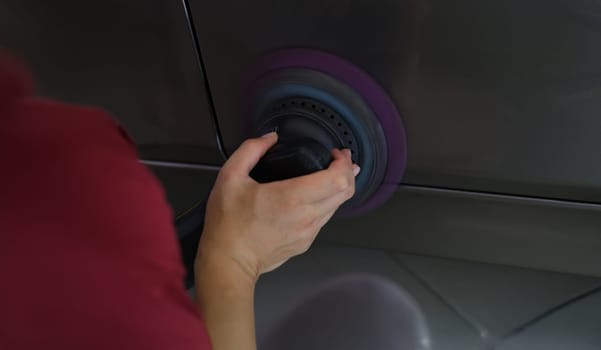 A man polishes a car cover, close-up. Scratch removal tool, abrasive polish, hard polishing disc, detailing