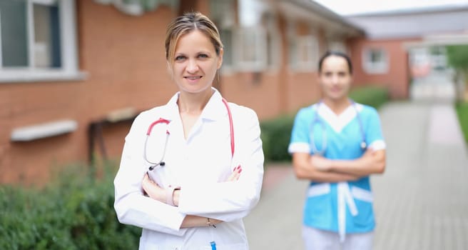 Woman doctor and nurse stand near the clinic, close-up, blurry. Rehabilitation center staff for alcoholics