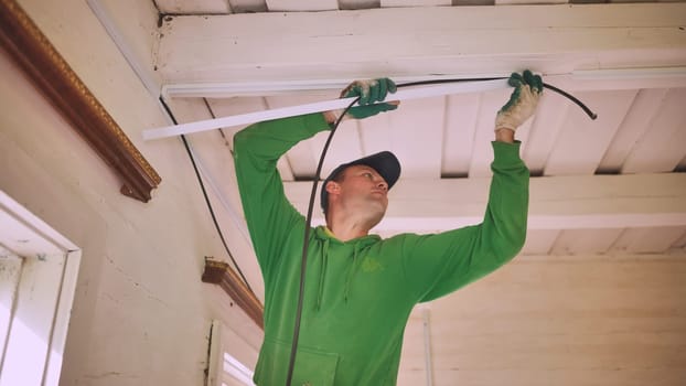 An electrician works with a drill to create electrical wiring