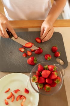 women's hands slicing berries for dessert.