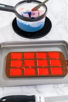 Filling silicone mold with red and blue melted chocolate to make chocolate stars for patriotic lemon cupcakes.