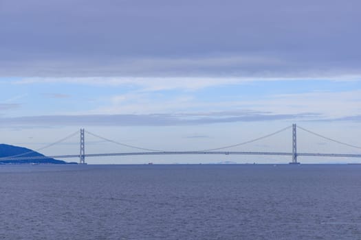 Low cloud layer over Akashi suspension bridge and calm blue water. High quality photo