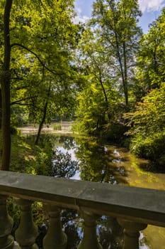 Small stream in beautiful park with colorful surroundings seen from small concrete bridge with beautiful decorations