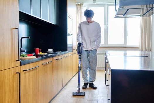 Young guy doing vacuuming at home. Cleaning den, cleanliness, hygiene, youth concept