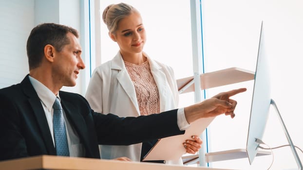 Two business people talk project strategy at office meeting room. Businessman discuss project planning with colleague at modern workplace while having conversation and advice on financial report. Jivy