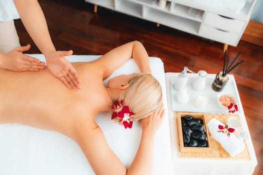 Caucasian woman customer enjoying relaxing anti-stress spa massage and pampering with beauty skin recreation leisure in day light ambient salon spa at luxury resort or hotel. Quiescent