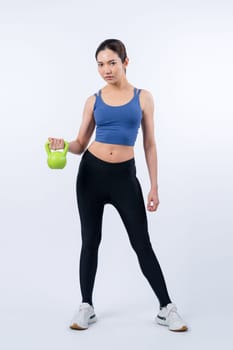 Vigorous energetic woman doing kettlebell weight lifting exercise on isolated background. Young athletic asian woman strength and endurance training session as body workout routine.