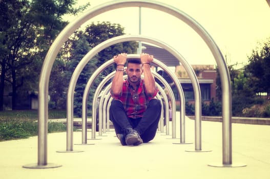 A man sitting on the ground in front of a metal structure