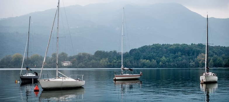 A group of boats floating on top of a lake. Photo of a serene lake with a fleet of colorful boats peacefully gliding on the water