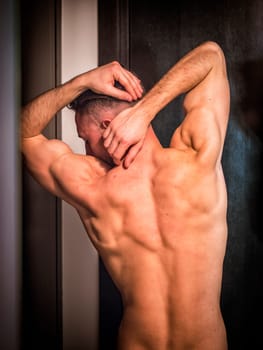 A shirtless man with his hands on his head