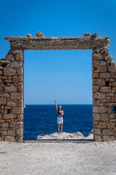 Young woman dressed in crochet at stone door in Paralia Firopotamos, Milos