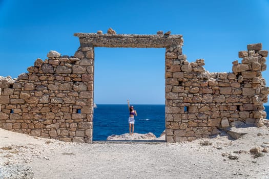 Young woman dressed in crochet at stone door in Paralia Firopotamos, Milos