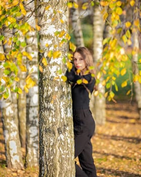 A beautiful girl posing near a birch tree in an autumn park