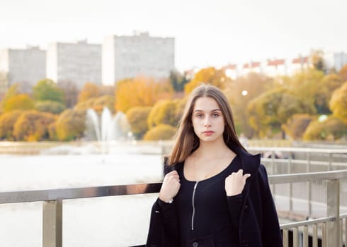 Portrait of a girl on a bridge near a pond in a city park