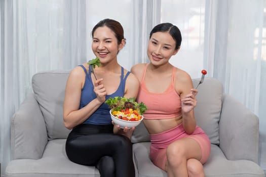 Young sporty Asian women in sportswear holding salad bowl together fill with vibrant of fruit and vegetable. Natural youthful and fit body lifestyle with balance nutrition and home exercise. Vigorous