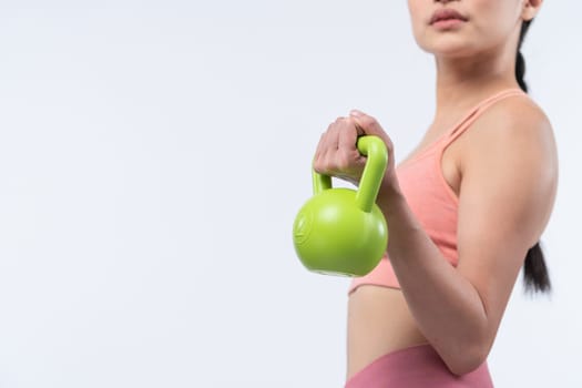 Vigorous energetic woman doing kettlebell weight lifting exercise on isolated background. Young athletic asian woman strength and endurance training session as body workout routine.