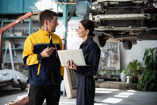 Two vehicle mechanic working together, conduct car inspection with laptop. Automotive service technician in uniform carefully make diagnostic troubleshooting to identify error. oxus