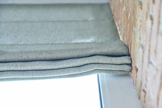 Close-up of roman blinds with gray linen fabric. Design, functional protection, fashionable modern window decoration design at home