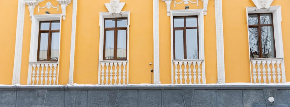 Elegant classical windows decorated with stucco ornaments on beige antique facades. Vintage classic architecture.