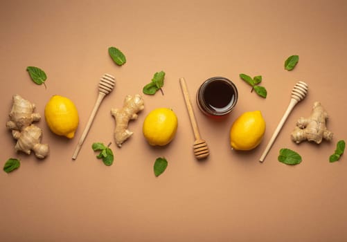 Composition with lemons, mint, ginger, honey in glass jar and honey wooden dippers top view. Food for immunity stimulation and against seasonal flu. Healthy natural remedies to boost immune system.