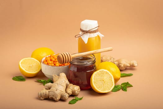 Composition with detox drink, sea buckthorn berries, lemons, mint, ginger, honey in glass jar. Food for immunity stimulation and against flu. Healthy natural remedies to boost immune system.