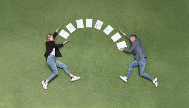 Between a man and a woman documents in a semicircle on a green cover, close-up, top view. Freelance collaboration, team concept