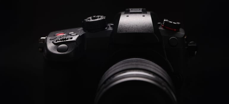 Digital black camera on a black background, close-up. Content creation, professional equipment for a video blogger, streamer