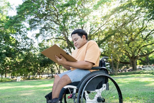 A young person in a wheelchair sketching in a sunny park, surrounded by vibrant green trees and grass.