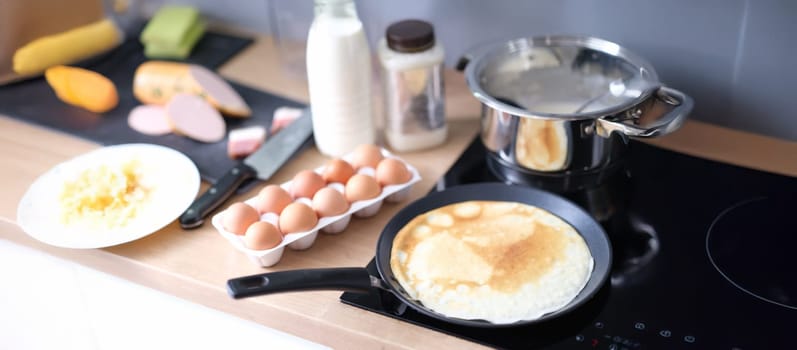 Thin pancake in a frying pan, cooking at home, close-up. Bio ingredients for a pancake recipe. Kitchen surface