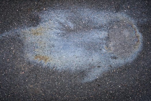 Gasoline or oil is creating a colorful stain on asphalt road.