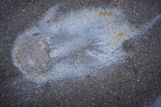 Gasoline or oil spill creating a colorful stain on asphalt road. Gasoline or oil is making a stain with rainbow reflections on an asphalt road